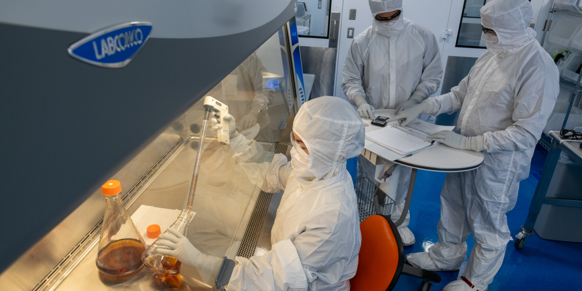 Scientist filling containers inside ISO Class 5 environment provided by the Logic+ Class II, Type A2 Biosafety Cabinet. 